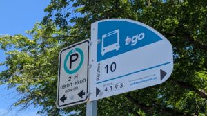 Close up of a street sign that indicates a bus stop for Route 10 on the right of the sign, and 2-hour parking to the left of the sign.